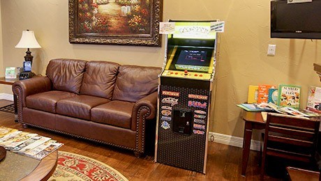 Brown leather couch next to arcade game in dental office waiting area