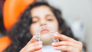 Closeup of teen girl holding clear aligner