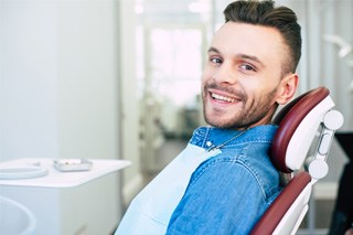 Man in denim jacket smiling in dental chair