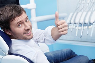 Man in dental chair giving a thumbs up