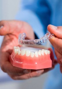 Close up of patient lifting a clear aligner from a model dental arch