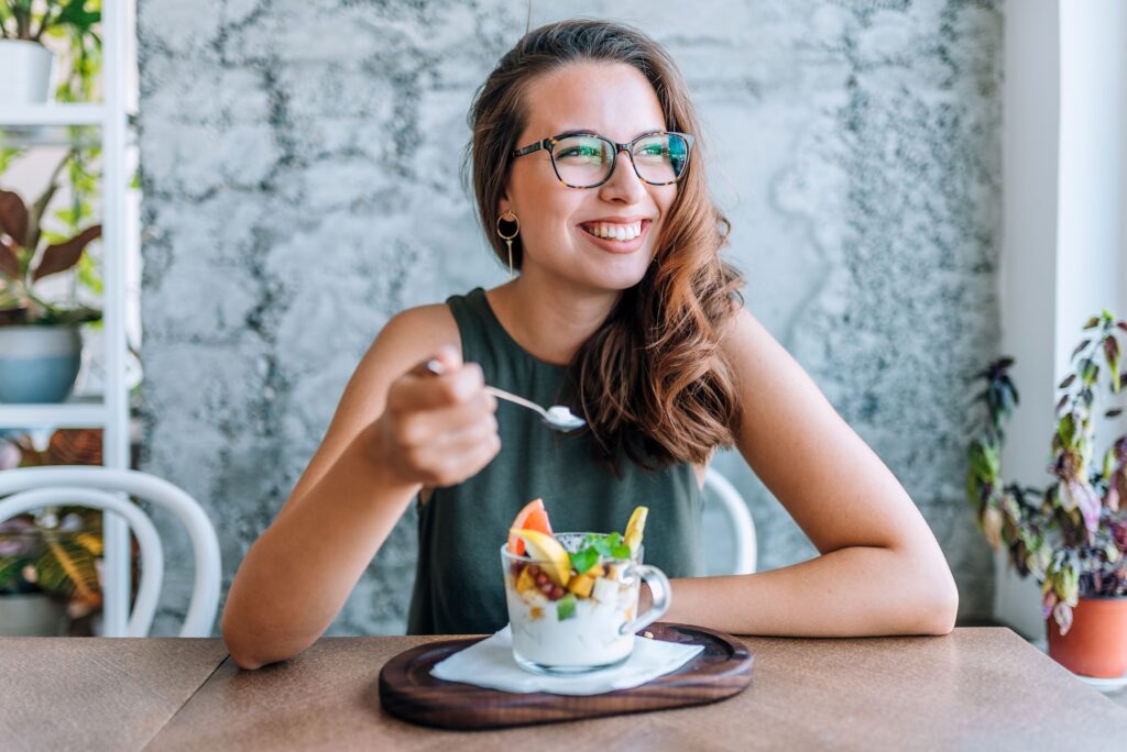 Woman in glasses eating yogurt dish with fruit