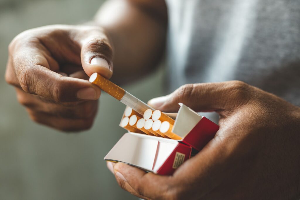 Hands pulling a cigarette out of the packet